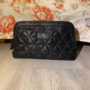 Molly Marais Neccessär - En svart neccessär med guldiga detaljer från Molly Marais Copenhagen. Okej skick, men lite smutsig på insidan, samt en fläck på framsidan. 