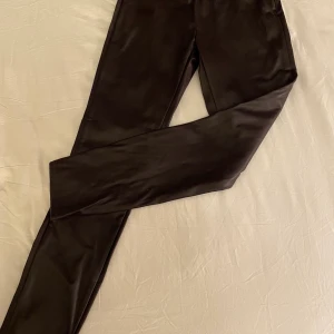 Skinnbyxor från Wera - Snygg ”skinnbyxa” i tight modell. Nya och helt oanvända. Bred resår i midjan och dragkedja i ena sidan.  Töjbart tyg, 100% PU. Tvättbara.