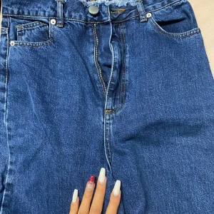 Esos Jeans  - Ett par möekblåa denim jeans som e tajt uppe och lös där nere, lite som momjeans, får en fin form och sitter som ett smäck! Har fina detaljer både vid midjan och vid fötterna 