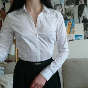  - Jättefin figursydd vit skjorta med svarta prickar och långa ärmar från H&M. Väldigt tunt och skönt material. Helt oanvänd då den är sydd för att passa någon längre (är själv 159). Perfekt skick. 