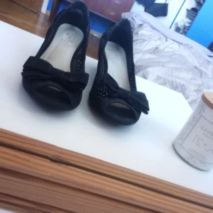  - Svarta skor med lita klack och rosett vid tårna. Använda ett fåtal gånger och i bra skick.