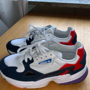  - Ett par Adidas i populära modellen ”Falcon”. Använda några få gånger men ser ut som helt nya.  Färg: vit/blå med inslag av röd/lila 