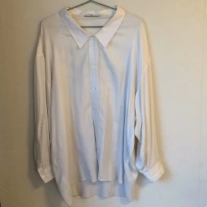  - Vit over-sized skjorta från ACNE. Det står att det är en storlek 36, men den skulle sitta bra på allt från en small till en large. Armarna är långa och pösiga. Kragen är styv och knapparna i pärlemor.   Skjortan är i behov av kemtvätt, då den har någon liten fläck (kan skicka bilder på dessa) och är lite smutsig i ärmarna. Eventuellt klarar den även av att handtvättas (har dock ej provat detta).   Material: 100% viskos