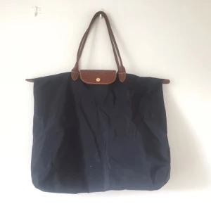  - Väska från Longchamp, 42x37cm. Själva grejen man drar i i dragkedjan har trillat av, men dragkedjan är hel i övrigt. Går att sätta dit en nyckelring eller liknande ifall en tycker det är jobbigt att dra. +42 för frakt 