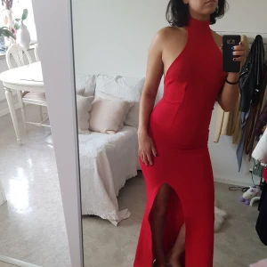  - Röd maxi klänning med choker och öppen rygg samt axlar. Passar perfekt till balen som till en middag.  Använd en gång och är i nytt skick. Möts upp i Göteborg. Köparen står för frakten. 