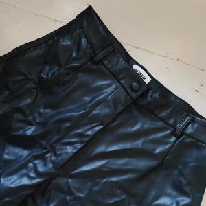SKINNBYXOR - WEEKDAY - Byxor i fake skinn från Weekday. Kortare modell och vida i benen. Använda fåtal gånger. Möts på Södermalm och vid frakt står köparen för kostnad!