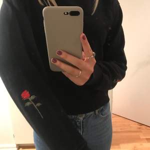 Lite kortare modell av sweatshirt med en ros på bäda ärmarna