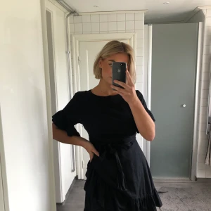 Svart klänning  - Snygg klänning med volanger vid kjol & armar. Fint knyte runt midjan🌹