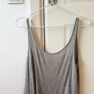 - Grått ribbat linne med djup urringning i ryggen, storlek xs, men skulle säga att den passar en S eller liten M med. Från Cubus.