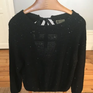  - Svart stickat tröja med knytning i nacken. Små paljetter insydda i stickningen! Storleken är liten och passar en 36/38 Jätte fin och fint skick! 