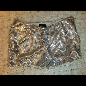  - Silvershorts med paljetter i storlek 36. Högmidjade med dragkedja som man öppnar och stänger med på sidan. Aldrig använda!