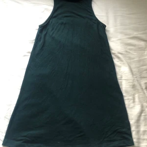 Klänning - Enkel, snygg och flowig klänning. Har halterneck och inga ärmar. Riktigt skön! Färgen blir mer rättvis på andra bilden. Det är grön