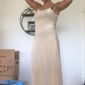 Mysig långklänning - Bekväm långklänning i skimrigt beige/nude färg. Storlek L enligt lapp, men vill en inte att den ska sitta för tight så passar den bättre en M. Jag är 175cm för referens. ”REA” på alla annonser! 2 varor 10%, 3 varor 15%, 4 eller fler varor 20%!  45kr frakt oavsett antal varor, om varan är lätt sänks frakten. Jag ansvarar inte för postens slarv.