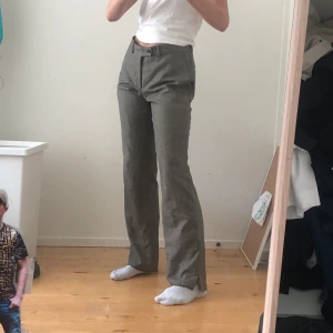 Bruna kostymbyxoe - Typ brungrå. Jag har klippt ett till hål där knappen ska in så dom kan bli tajtare i midjan om man vill. Pyttelite sönder längst ner på ena benet. Såhär sitter dom på mig som är 174 cm