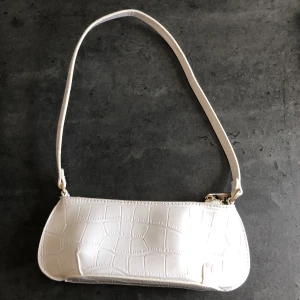OANVÄND baugette väska 🦋🤍 - En så fin shoulder bag från ASOS! Den är vit med krokodilmönster med guldiga detaljer. Köpt här på plick då den var i nyskick och jag har aldrig använt den så den är fortfarande helt oanvänd!! Skriv gärna till mig vid frågor💜✨