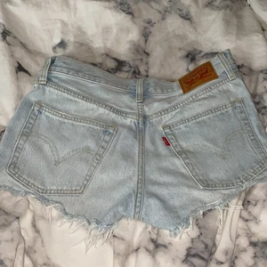 Levis 501 shorts W26 - Ett par Levis 501 shorts i storlek 26. Säljer eftersom de inte passar mig längre. Använda några fåtal gånger. OBS plagget ser lite ”washed” ut i materialet, men det är på grund av dåligt ljus när jag tog bilden. Det är alltså vanliga ljusblå shorts.