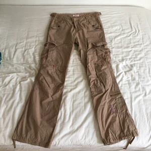 Beiga cargobyxor - Gott skick minus ett slitet snöre vid foten (bild 3). Passar 34-38 då midjan går att reglera. Jag har 38 och de är tajta på mig. Bra längd på mig som är 167cm. Frakt tillkommer.