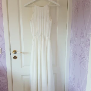 Vit långklänning med slits  - Jättefin klänning med resår i midjan och slits fram vid ena benet som går upp till låret. Endast använd en gång så är i nyskick 💞 köpte för 600. Frakt ingår i priset!
