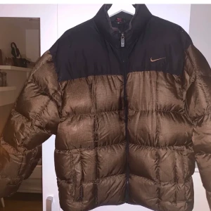 Pufferjacka från nike - Sjukt snygg och unik jacka från Nike i strl M. Köpte den här på plick men den va tyvärr förstor:( den är köpt vintage och du lär vara den enda med denna jackan😉 brun och svart utan några defekter. BUDET LIGGER PÅ 1520 avslutas ikväll 3/12 kl 22:00❤️❤️ buda minst 20 kr över!