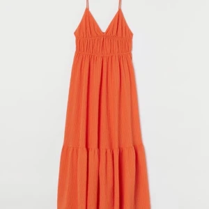 Orange klänning - En lång, v-ringad klänning från h&m. Den har reglerbara axelband. Bilder från hemsidan då den är oanvänd. Nypris: 499 kr