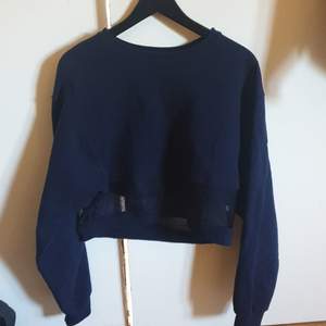 Snygg croppad sweatshirt i marinblått som är använd fåtal gånger, passar jättebra med spetsbh eller liknande under! Väldigt fint skick, köpare står för frakt