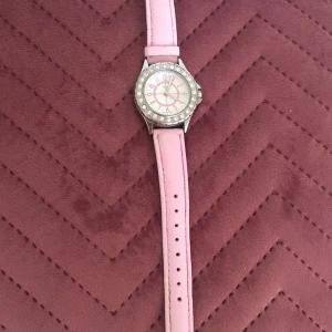 Regal klocko - En cool klocka i en ljusrosa färg, ger en 2000s vibe. Går ungefär 3 minuter för försent, men går nog att fixas av den som fattar klockor. Frakten är inte en del av priset. Obs, min lillasyster har ritat på tråden runt armbandet men det är knappt synligt.