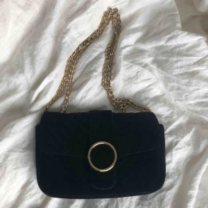  - En trendig väska i svart velvet som har justerbart band. Fint skick. Hör av er om frågor. Frakt tillkommer