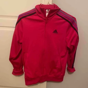  - Adidas tröja med krage i fint skick . Mörk rosa med mörkblå, lika och ljuslila ränder. 