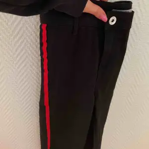 Svarta jeans med cool röd stripe längs benen. Använda ett fåtal gånger. Högmidjade och slimfit. Köpta från Bershka. Frakt ingår ej och fler bilder kan skickas vid intresse. 