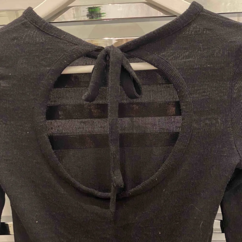 Svart tröja från H&M. Superfin cutout i ryggen som man knyter med en rosett. Lappen är bortklippt från tröjan så vet inte storleken, men tror xs för den är ganska liten. En maska är dragen så det är ett litet sträck på tröjan (se sista bild). Toppar.