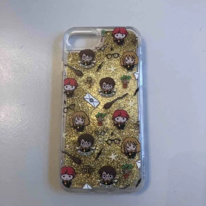  - Mobilskal med Harry Potter-tryck och guldigt glitter som ”flyter” runt. Passar iPhone 6/7/8. Aldrig använt, endast testad. 