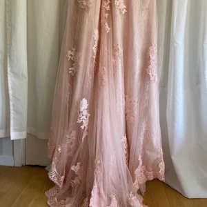 Balklänning - Rosa balklänning måttbeställd från Hebeos. Helt oanvänd. Passar mig som är 173 cm när jag bär låga klackar. Nypris 1400kr Bär vanligtvis S/M men klänningen är måttbeställd efter dessa mått: Byst 99cm Midja 77cm Höfter 107cm Nyckelben till marken 145cm Längd 173cm