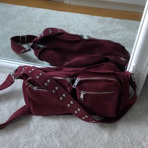 Norells bag - Väska i vinröd färg i mockainspirerat material. Jättepraktiskt och snygg. Säljer pga använder inte längre.