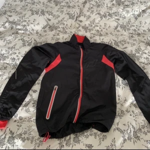 Träningsjacka  - Tunn träningsjacka perfekt till vår, sommar, höst. Använd men fortfarande i bra skick, tyvärr för liten nu för mig. Svart med korallfärgade detaljer och en ficka. Storlek 36