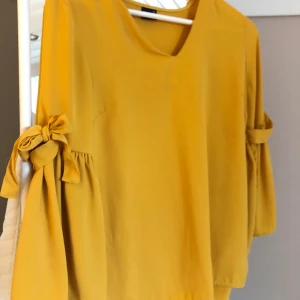 senapsgul blus  - senaps gul jättefin blus med knytningar vid ärmarna från ginatricot i storlek 36. aldrig använd 