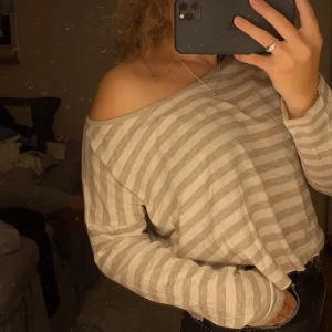 Långärmad tröja  - Randig långärmad ”one-shoulder” tröja som sitter på strl XS-M. Knappt använd