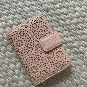 Beige mönstrad plånbok - Beige mönstrad plånbok från Glitter. Bra skick men lite avskavt vid låsflärpen (man ser det på första bilden). Köparen står för frakt