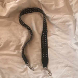 Väskband med nitar - Ett svart väskband med detaljer i mycket bra skick från Nelly. Köpare står för frakt ✨
