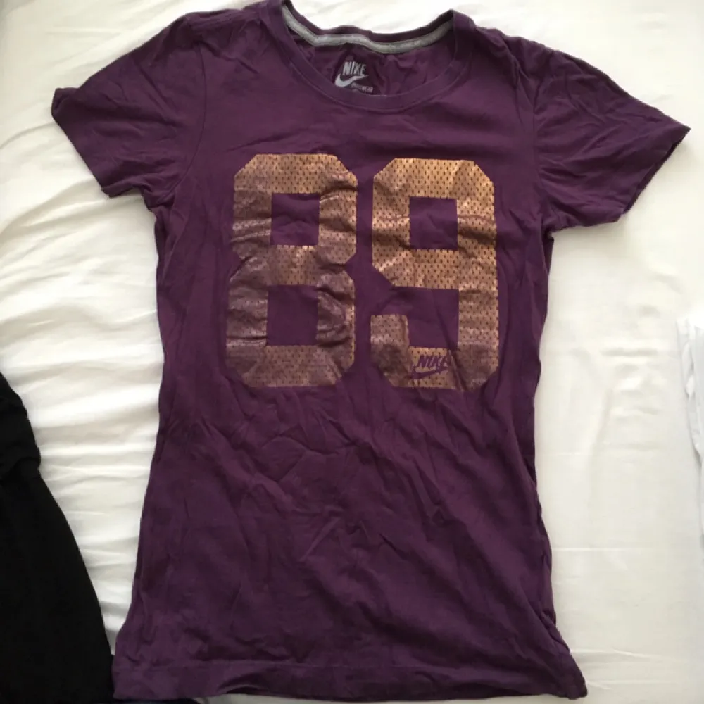 Fin lila tshirt från Nike med guld detaljer. Använd en gång, säljer för använder den aldrig. Storlek xs men passar en s med :). T-shirts.