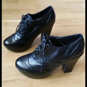  - Svarta platåklackar. Klack 11 cm, platå 3 cm. Använd fåtal gånger, finns lite repor på insidan av vänster klack. 