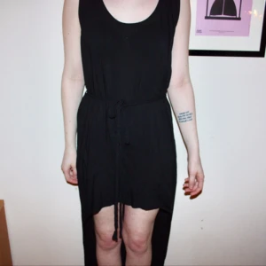  - Svart klänning från Solo. Flätat band i midjan som man kan ta bort. Använd max 5 gånger. Lång i bak, kortare i fram.  Frakt kostar 30kr. Samfraktar. Kan mötas upp, använder helst swish.