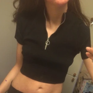  - Snygg crop top / magtröja från Gina Tricot. Strechig och aningen ribbad. Svart med hög hals och dragkedja. Aldrig använd