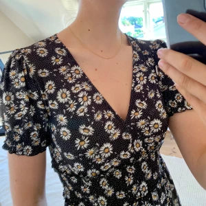 Blommig klänning - Den PERFEKTA sommarklänningen. Så himla gullig och dessutom världens skönaste material. Knappt använd, och förtjänar ett nytt hem. Svart med vita blommor. Pris kan diskuteras!