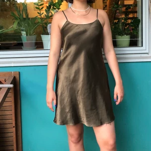 Skimrande slip-dress med justerbara band - Väldigt fin mörkgrön klänning i gott skick, i storlek xs/s skulle jag säga. Personen på bilden är 172cm lång. Kan mötas i Gbg eller så står köpare för frakt.