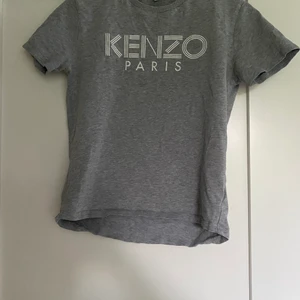 Kenzo T-shirt - Säljer min Kenzo t-Shirt pga liten storlek. Den är i bra skick, helt äkta köpt på Harrods i England. Är grå med kenzo loggan på bröstet, ny pris 800kr