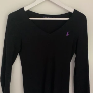 Tröja Ralph Lauren - Svart tröja med lila märke från Ralph Lauren i nyskick. Storlek xs! 150kr + frakt