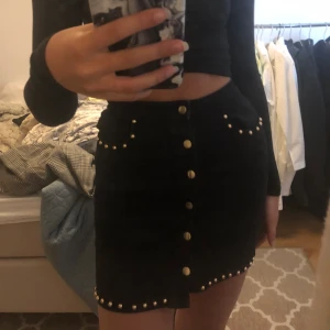 Svart minikjol med guldiga nitar, strl34 - Svart minikjol från missguided med guldiga detaljer. Sparsamt använd och sitter fint på kroppen. Har S i vanliga fall så den är väldigt stretchig. Frakt tillkommer!