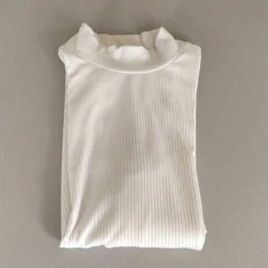 Vit ribbad topp med halv polo - Ärmarna kommer till ovanför armbågen. Använd men i felfritt skick! Vi delar på frakten om du köper mer än ett plagg! ✨