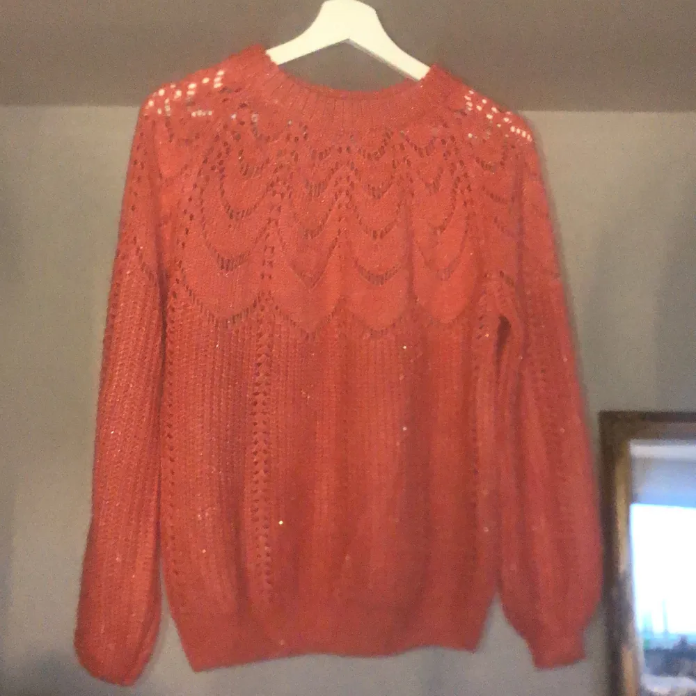 En rosa/aprikos färgad stickad tröja med glitter tråd in sytt. Mönstrad upptill . Stickat.