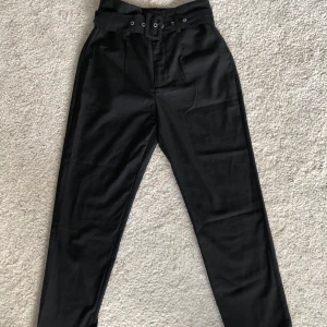 Svarta kostymbyxor  - Svart kostymbyxor med skärp i midjan. Använda ett fåtal gånger.